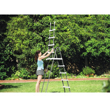 O femeie montează o scară de piscină gri cu trepte albe pe un gazon într-o grădină luminoasă și spațioasă.