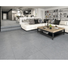 Gresie gri de format mare cu aspect de piatră într-un living modern și luminos, cu canapea albă și bucătărie deschisă.