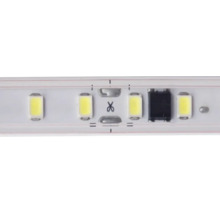 Vedere detaliată a unei benzi LED cu LED-uri și punct de tăiere marcat prin simbolul foarfece.
