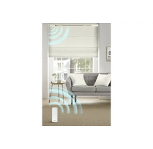 Jaluzea romană electrică în camera de zi, controlată prin telecomandă cu semnal wireless, montată la fereastră deasupra unei canapele gri.