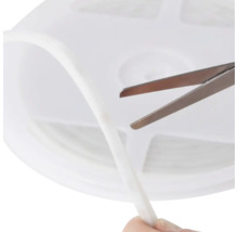 Bandă LED albă flexibilă scurtată cu o foarfecă metalică pe o rolă de plastic.