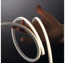 Bandă LED neon flexibilă îndoită de o mână, demonstrând flexibilitatea și lumina albă caldă.