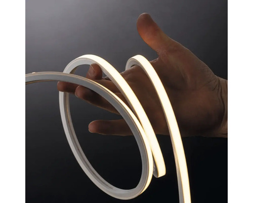 Bandă LED neon flexibilă îndoită de o mână, demonstrând flexibilitatea și lumina albă caldă.