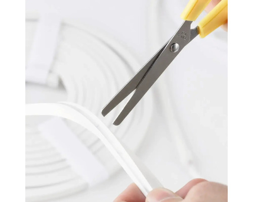 Foarfecă tăind un profil flexibil din silicon pentru benzi LED.