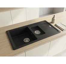 Chiuvetă încastrată cu o cuvă și jumătate și picurător din material compozit într-un blat de lemn deschis și bucătărie albă.