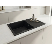 Chiuvetă de bucătărie neagră cu picurător montată într-o insulă de bucătărie modernă și deschisă la culoare.