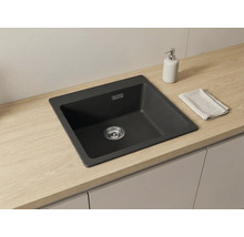 Chiuvetă încorporată modernă din material compozit închis la culoare într-un blat deschis cu aspect de lemn, design minimalist și organizat.