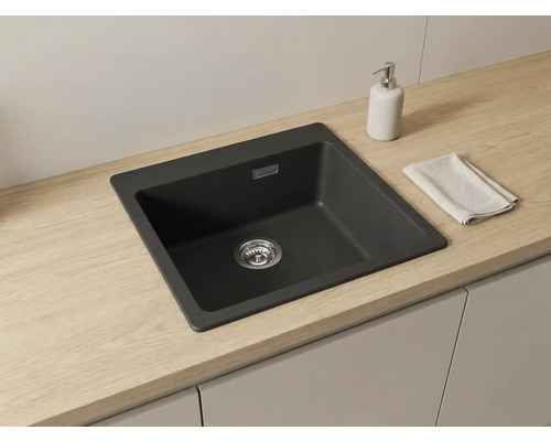 Chiuvetă încorporată modernă din material compozit închis la culoare într-un blat deschis cu aspect de lemn, design minimalist și organizat.