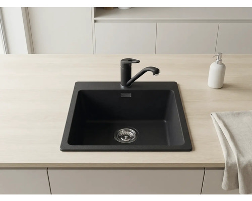 Chiuvetă încorporabilă neagră din compozit de granit cu baterie de bucătărie neagră pe un blat deschis la culoare într-o bucătărie modernă.