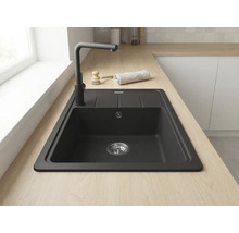 Chiuvetă încastrată neagră din compozit de cuarț cu picurător pe un blat din lemn deschis cu baterie neagră într-o bucătărie luminoasă.