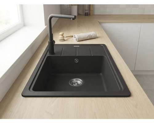 Chiuvetă încastrată neagră din compozit de cuarț cu picurător pe un blat din lemn deschis cu baterie neagră într-o bucătărie luminoasă.