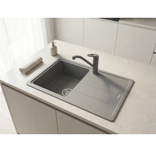 Chiuvetă încorporabilă modernă din material compozit cu picurător și baterie pe un blat de lucru într-o bucătărie luminoasă și organizată.