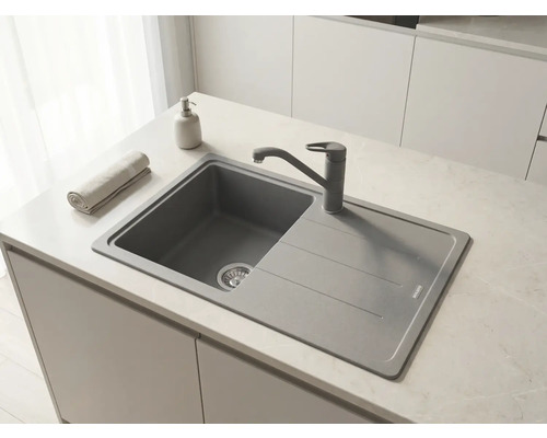 Chiuvetă încorporabilă modernă din material compozit cu picurător și baterie pe un blat de lucru într-o bucătărie luminoasă și organizată.