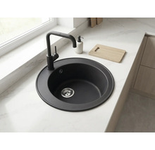 Chiuvetă de bucătărie rotundă neagră cu baterie asortată, încorporată într-un blat de lucru deschis cu aspect de marmură.