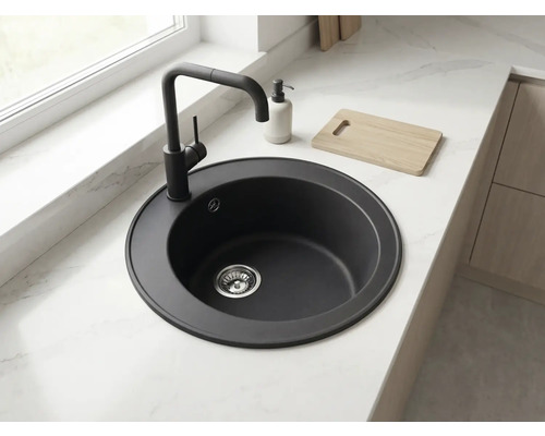 Chiuvetă de bucătărie rotundă neagră cu baterie asortată, încorporată într-un blat de lucru deschis cu aspect de marmură.