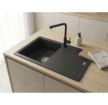 Chiuvetă de bucătărie încorporabilă de culoare neagră cu baterie asortată pe un blat de lemn deschis într-o bucătărie modernă.