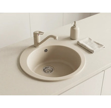 Chiuvetă de bucătărie rotundă din material compozit cu baterie monocomandă asortată, dozator de săpun și lavetă pe un blat de lucru deschis.