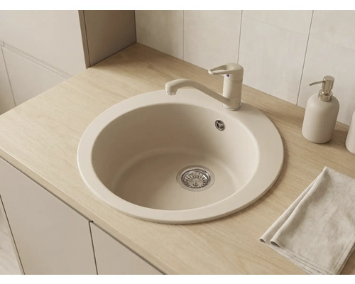 Chiuvetă de bucătărie rotundă încastrată, bej, din material compozit, cu baterie monocomandă asortată pe un blat cu aspect de lemn deschis.