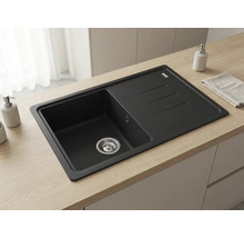 Chiuvetă încorporată neagră cu picurător pe un blat din lemn deschis, într-o bucătărie luminoasă cu design modern.