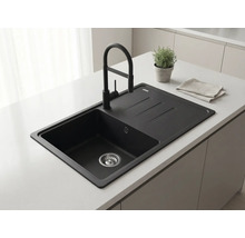 Chiuvetă încorporată neagră cu picurător și baterie neagră pe o insulă de bucătărie deschisă la culoare într-o bucătărie modernă.