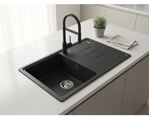 Chiuvetă încorporată neagră cu picurător și baterie neagră pe o insulă de bucătărie deschisă la culoare într-o bucătărie modernă.