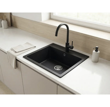 Chiuvetă încorporată modernă din compozit negru cu baterie de bucătărie înaltă negru mat pe un blat alb într-o bucătărie luminoasă.