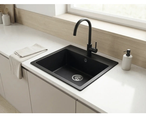 Chiuvetă încorporată modernă din compozit negru cu baterie de bucătărie înaltă negru mat pe un blat alb într-o bucătărie luminoasă.