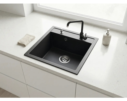 Chiuvetă de bucătărie modernă, pătrată, din compozit negru, cu baterie, încorporată într-un blat deschis la culoare într-o bucătărie luminoasă.