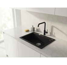 Bucătărie modernă cu chiuvetă încorporabilă neagră și baterie de bucătărie neagră pe un blat de lucru deschis la culoare cu aspect de marmură.