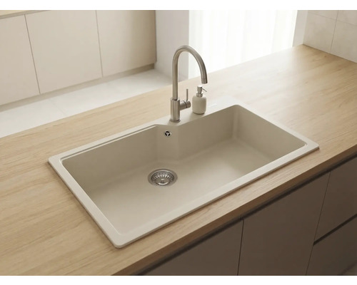 Chiuvetă de bucătărie încorporabilă din compozit bej cu baterie din oțel inoxidabil și dozator de săpun pe un blat de lemn.