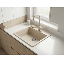 Chiuvetă de bucătărie bej cu baterie asortată pe un blat alb și dulapuri din lemn deschis într-o bucătărie luminoasă.