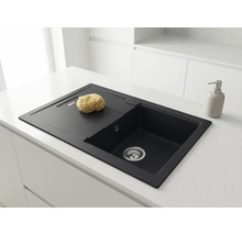 Chiuvetă neagră din compozit de granit în blat alb. O singură cuvă cu picurător. Bucătărie luminoasă și minimalistă.