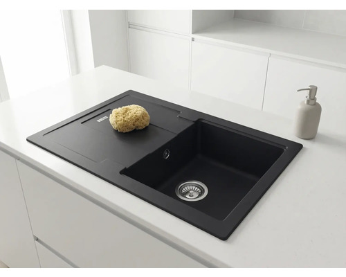 Chiuvetă neagră din compozit de granit în blat alb. O singură cuvă cu picurător. Bucătărie luminoasă și minimalistă.