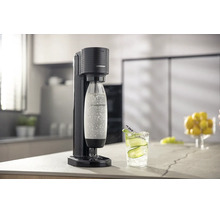 Aparat pentru apă minerală SodaStream Terra negru într-o bucătărie luminoasă și organizată, cu o sticlă de carbonatare și un pahar cu apă.