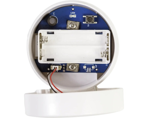 Vedere interioară a unui dispozitiv electronic cu compartiment pentru baterii gol pentru două baterii și o placă de circuit albastră.