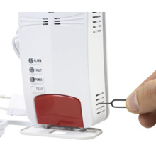 Detector de gaz alb cu martori luminoși pentru alarmă, defecțiune și alimentare. O mână introduce o cheie de resetare în fantele laterale.