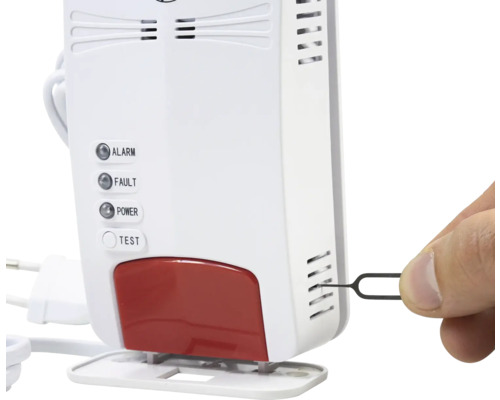 Detector de gaz alb cu martori luminoși pentru alarmă, defecțiune și alimentare. O mână introduce o cheie de resetare în fantele laterale.