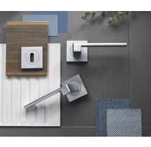 Set modern de mânere pentru uși cu aspect cromat și rozetă pătrată, prezentat cu mostre de materiale precum lemn, gresie și textile.