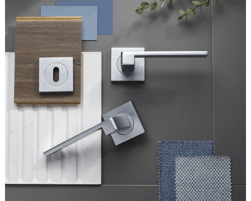 Set modern de mânere pentru uși cu aspect cromat și rozetă pătrată, prezentat cu mostre de materiale precum lemn, gresie și textile.