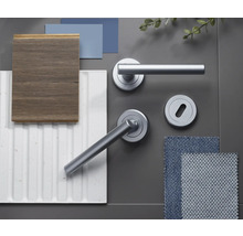 Colaj de materiale cu mânere de ușă gri mat pe rozetă, lemn închis la culoare, panou de perete alb cu structură canelată și mostre de țesătură albastră.