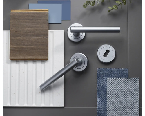 Colaj de materiale cu mânere de ușă gri mat pe rozetă, lemn închis la culoare, panou de perete alb cu structură canelată și mostre de țesătură albastră.