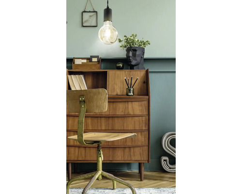 Birou în stil vintage cu secretariat din lemn, scaun rotativ din metal și corp de iluminat suspendat decorativ pe un perete verde.