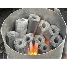 Brichete de cărbune hexagonale aprinse cu gaură într-un aprinzător pentru grătar.