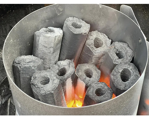 Brichete de cărbune hexagonale aprinse cu gaură într-un aprinzător pentru grătar.