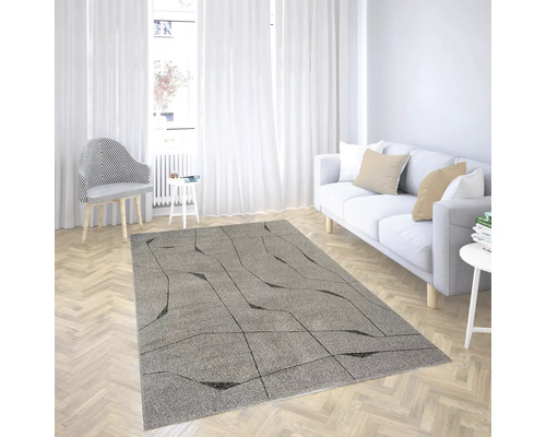 Covor gri modern cu model geometric negru într-o sufragerie luminoasă cu canapea albă și parchet tip brăduț.