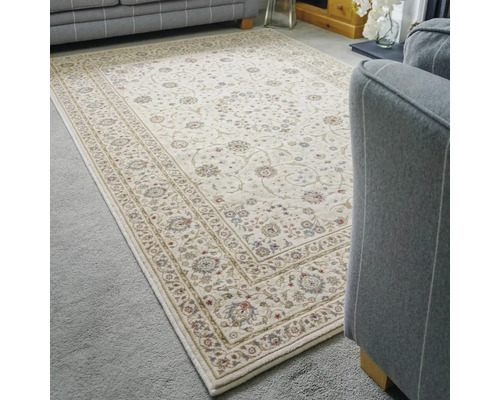 Covor oriental cu model floral și bordură într-o cameră de zi luminoasă cu canapele gri.