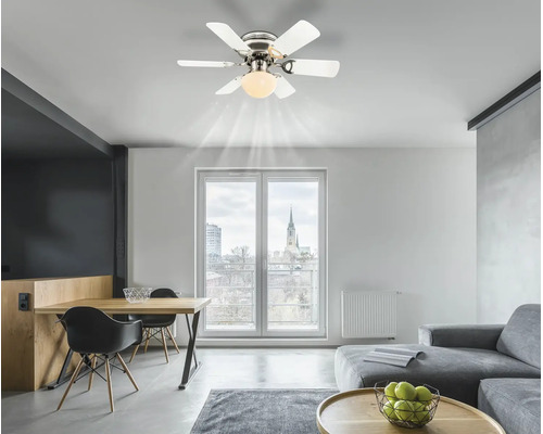 Ventilator de tavan modern cu șase palete albe și iluminat integrat într-o cameră de zi luminoasă și spațioasă, cu masă și canapea.