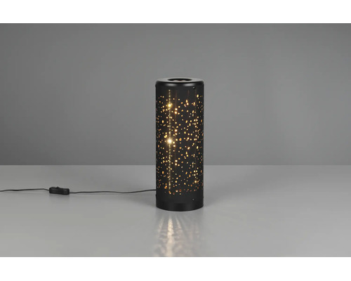 Veioză cilindrică din metal negru cu decor în formă de stele prin perforații și întrerupător pe fir, aprinsă.