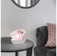Veioză decorativă în formă de scoică argintie cu o perlă roz luminoasă pe o masă rotundă într-o sufragerie.