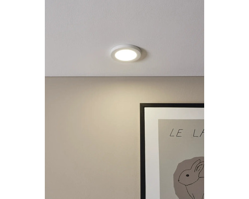 Plafonieră LED care luminează un perete deasupra unei rame de tablou.
